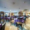 Una sala ristorante con tavoli apparecchiati con tovaglie viola.