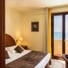 Camera da letto luminosa con vista mare, letto matrimoniale e mobili in legno.