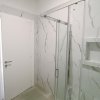 Bagno moderno con doccia e piastrelle marmoree.
