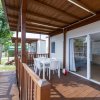 Terrazza con tavolo bianco e sedie sotto pergola di legno.