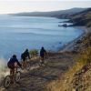Tre ciclisti su un sentiero polveroso lungo la costa.