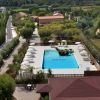 Vista dall'alto di una piscina con ombrelloni e vegetazione.