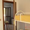 Stanza con letto a castello giallo, porta aperta verso una sala da pranzo con tavolo apparecchiato.