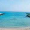 Spiaggia con sabbia dorata e acqua cristallina tra due scogliere.