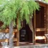 Casetta in legno con veranda e albero vicino.
