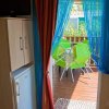 Porte con tende colorate, tavolo e sedie verdi all'aperto.