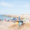 Spiaggia con ombrelloni colorati e persone che prendono il sole.