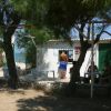 Persone sedute vicino a una casetta bianca tra gli alberi.