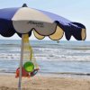 Ombrellone su spiaggia con mare sullo sfondo.