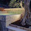 Piscina in pietra con albero illuminato.