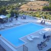 Piscina con lettini bianchi e panorama collinare.
