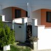 Facciata di una casa con portico e cancello nero.