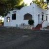 Casa bianca con archi e giardino alberato.