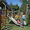 Parco giochi con scivolo e due persone sedute.