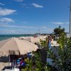 Ombrelloni beige su una spiaggia sabbiosa accanto al mare, con cielo azzurro e nuvole.