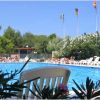 Piscina con sedie a sdraio, fiori e bandiere italiane e straniere al confine.