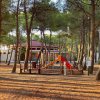 Parco giochi tra alberi con una struttura colorata.