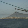 Reti da pesca sopra il mare con città sullo sfondo.