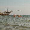 Persone su una tavola in mare, vicino a una struttura di legno.