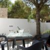 Tavolo con sedie nere e bicchieri di vino su terrazza, circondato da alberi e muro.