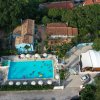 Vista aerea di piscina con ombrelloni e casette.