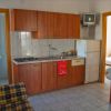 Cucina con mobili in legno, frigorifero, TV e accesso a bagno e camera.