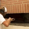 Un uomo inserisce una pala in un forno a legna.