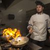 Cuoco in cucina con fiamma alta.