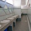Bagni pubblici con lavandini e piastrelle verdi.