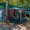 Area campeggio con tenda e bici sotto alberi.