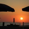 Tramonto visto da una spiaggia con ombrelloni.