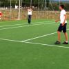 Tre persone giocano a calcio su un campo verde.