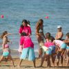 Bambini e adulti giocano sulla spiaggia con il mare sullo sfondo.
