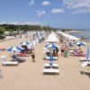 Spiaggia sabbiosa con ombrelloni e lettini.