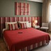 Camera con letto rosso e lampada da tavolo.