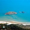Spiaggia sabbiosa con isole in lontananza e mare blu.