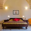 Camera con letto matrimoniale, poltrona arancione e soffitto a volta.