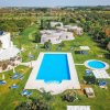 Una piscina all'aperto con lettini e giardino circostante.