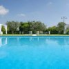 Area piscina con tende bianche e vegetazione verde sullo sfondo.