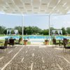 Patio con tavoli e sedie, vista sulla piscina e giardino sullo sfondo.