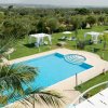 Piscina circondata da giardini, gazebo bianchi e lettini blu.