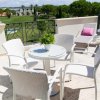 Terrazza con tavolino rotondo, sedie bianche, due lettini e cuscini rosa.