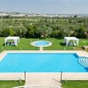 Una piscina con lettini e gazebo bianchi in un ampio giardino verde.