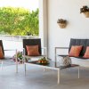 Set da esterno con divani, tavolino e cuscini arancioni su una terrazza.