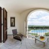 Stanza con letto e balcone arredato, vista su piscina e paesaggio.