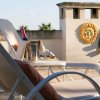 Lettino da terrazza con bottiglia in ghiaccio, decorazione solare sul muro.