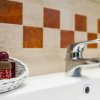 Lavandino con rubinetto lucido, cestino di prodotti da bagno accanto a piastrelle arancioni.