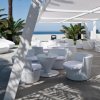 Area lounge all'aperto con sedie e tavolini bianchi moderni.