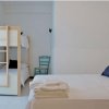 Camera con letto matrimoniale bianco, letti a castello e sedia verde.