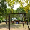 Parco giochi all'aperto con alberi, altalene e giochi per bambini.